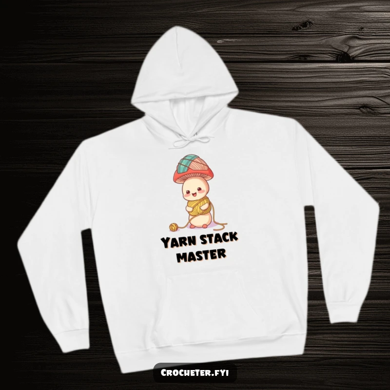 Funny hoodie showing a cheerful mushroom character attempting to balance a wobbly tower of colorful yarn balls, a whimsical crafting theme.