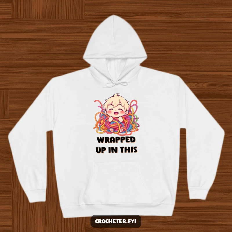 Funny hoodie showing a giggling character buried in a playful, tangled mess of vibrant yarn, perfect for cozy days.