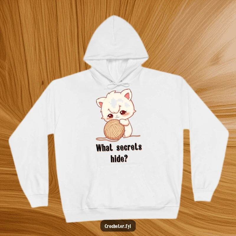 Funny hoodie featuring a character with a focused gaze, curiously poking a ball of yarn, representing inquisitive exploration.